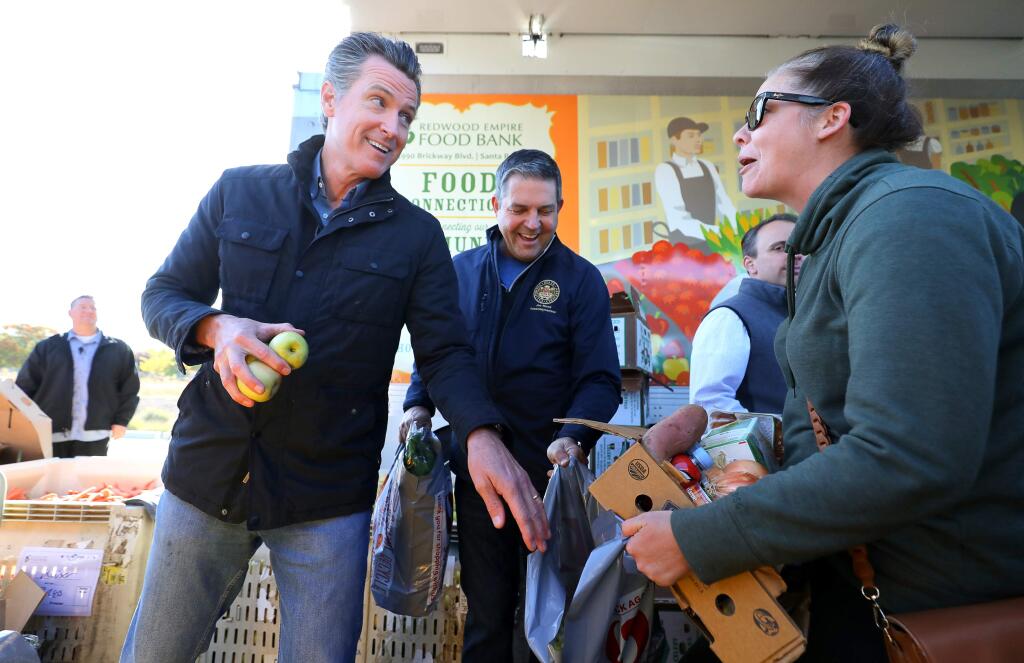 California Gov. Gavin Newsom, left, and Assemblymember Jim Wood help to hand out food at the Redwood Empire Food Bank's crisis truck in Santa Rosa on Wednesday, Oct. 30, 2019. (Christopher Chung/ The Press Democrat)