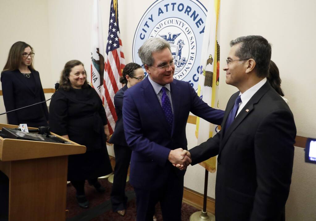 California Attorney General Xavier Becerra, right, shakes hands with San Francisco City Attorney Dennis Herrera during a press conference at San Francisco City Hall Monday, Aug. 14, 2017, in San Francisco. The state of California and city of San Francisco are suing the U.S. Department of Justice over President Donald Trump's sanctuary city restrictions on public safety grants. (AP Photo/Marcio Jose Sanchez)