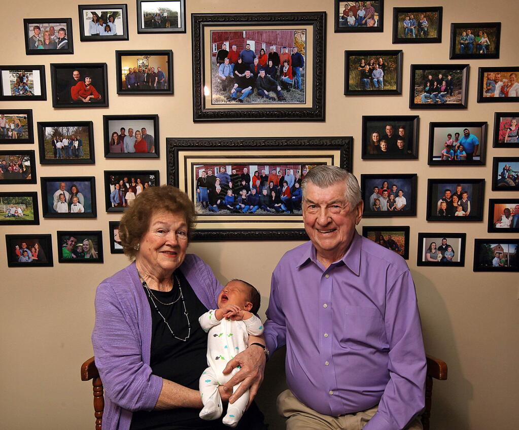 In this April 17, 2015 photo, Leo and Ruth Zanger sit with their 100th grandchild, Jaxton Zanger, in Leo's real estate office in Quincy, Ill. Jaxton was born April 8 to parents Austin and Ashleigh Zanger. For the numerically inclined, Jaxton was also No. 46 among the great-grandchildren. The Zangers also have 53 grandkids and one great-great-grandchild for a nice round 100. 'The good Lord has just kept sending them,' Leo Zanger said of the grandkids. 'We could start our own town.' (Phil Carlson/The Quincy Herald-Whig via AP)