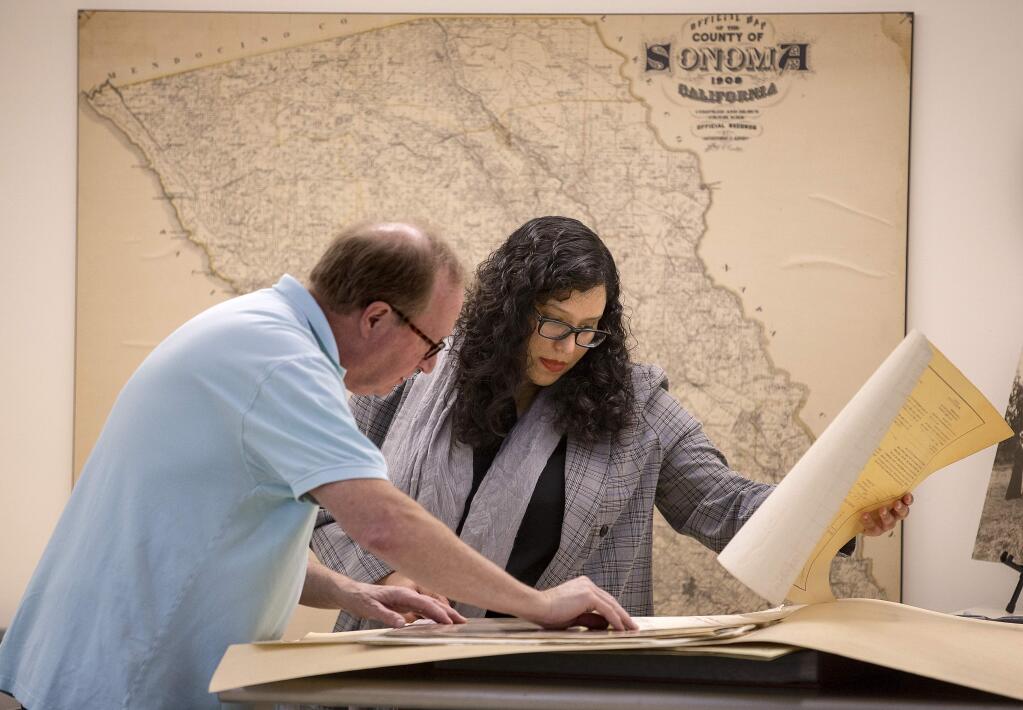 Sonoma County History and Genealogy librarian Zayda Delgado searches through old maps with David Proctor, who was looking for the location of his house when it was moved to build Hwy 101 60 years ago. (photo by John Burgess/The Press Democrat)