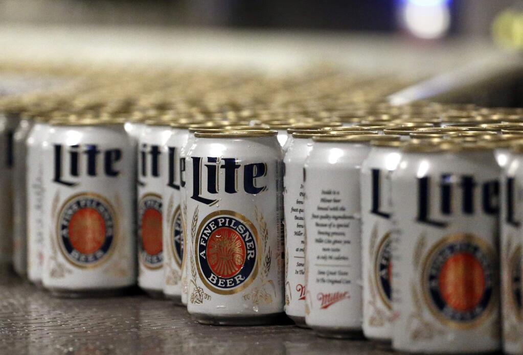 In this March 11, 2015 photo, newly-filled and sealed cans of Miller Lite beer move along on a conveyor belt, at the MillerCoors Brewery, in Golden, Colo. After turning down five offers, British-based brewer SABMiller, which sells beers including Miller Lite, Coors Light and Blue Moon in the U.S. and Puerto Rico through a joint venture with Molson Coors, on Tuesday, Oct. 13, 2015 accepted in principle an improved takeover bid worth 69 billion pounds ($106 billion) from Anheuser Busch InBev. Many analysts think that the merged company will be compelled to sell the Miller line of beers in the U.S. (AP Photo/Brennan Linsley)