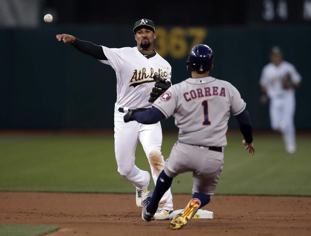 The Oakland Athletics' Marcus Semien, left, throws over the Houston Astros' Carlos Correa (1) to complete a double play on Josh Reddick during the second inning Wednesday, April 17, 2019, in Oakland. (AP Photo/Ben Margot)