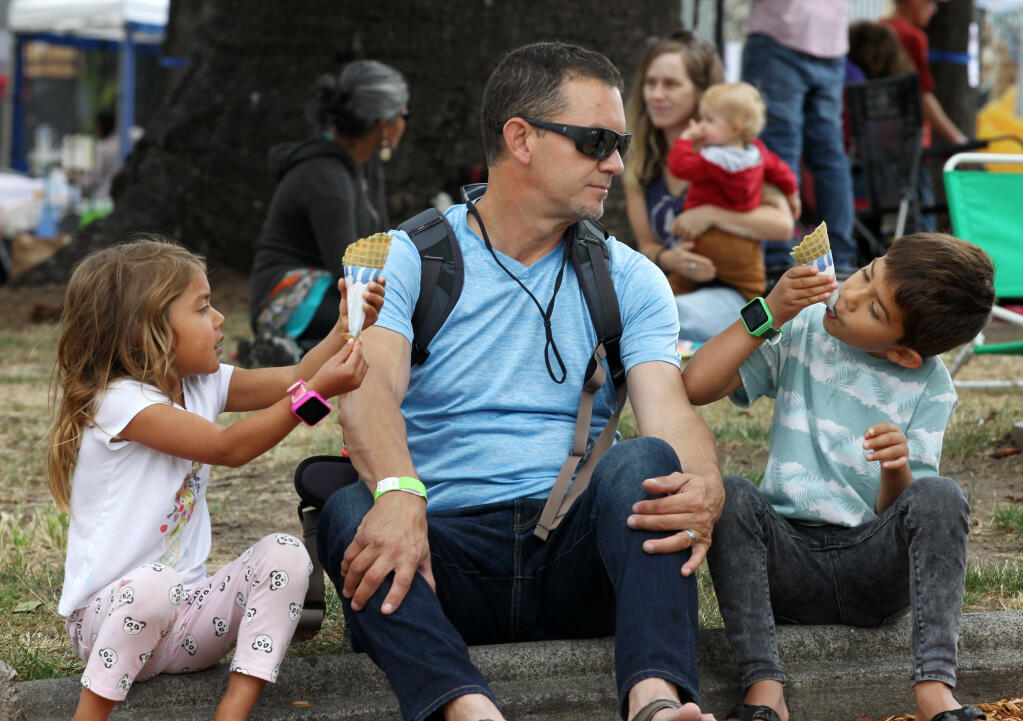 David Dorman, watches his children, Salma, 4, and Anderson, 6, all from Santa Rosa, eat ice cream cones at the Railroad Square Music Festival, Sunday, June 12, 2022, in Santa Rosa. (Darryl Bush / For The Press Democrat file)