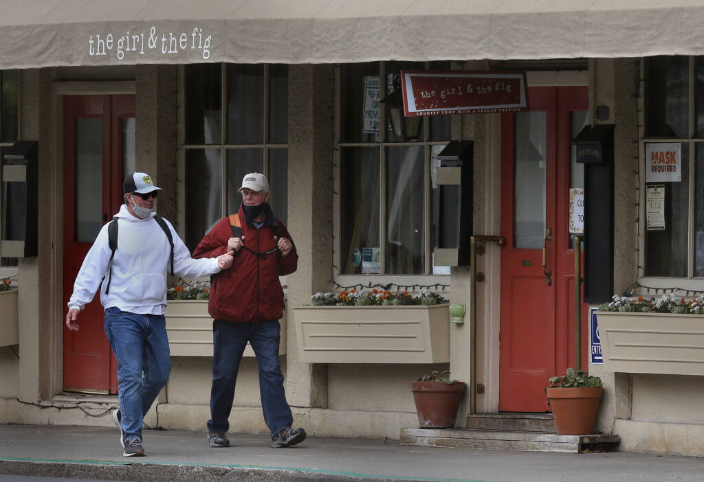 Neighbors Robert Tosti, left, and Ed Colteaux walk by The Girl and the Fig restaurant, which was temporarily closed on Thursday, Feb. 11, 2021. (Beth Schlanker/ The Press Democrat)