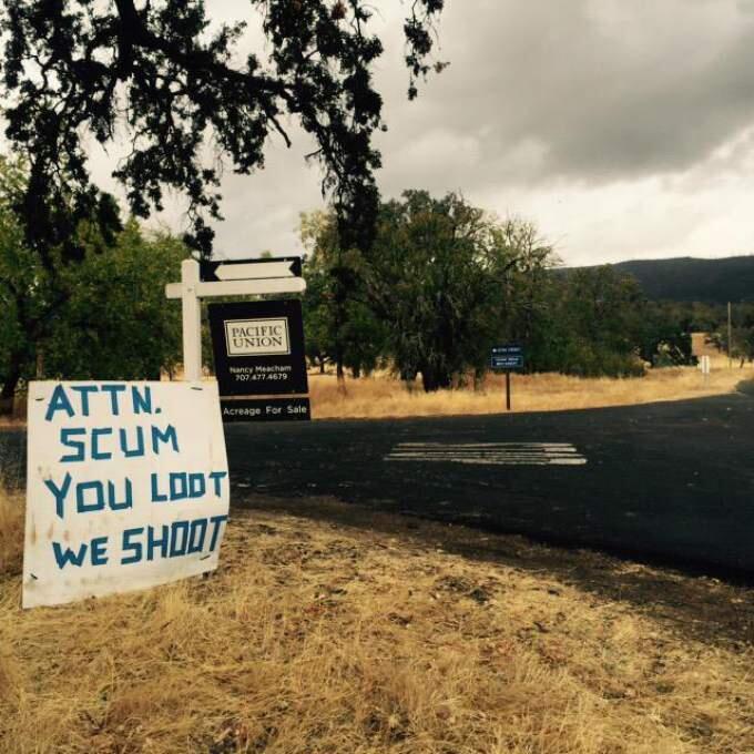 Signs discouraging looting dot the road to evacuation centers set up for people forced out of their homes from the Valley fire, Wednesday, Sept. 16, 2015. (ANGELA HART/ PD)