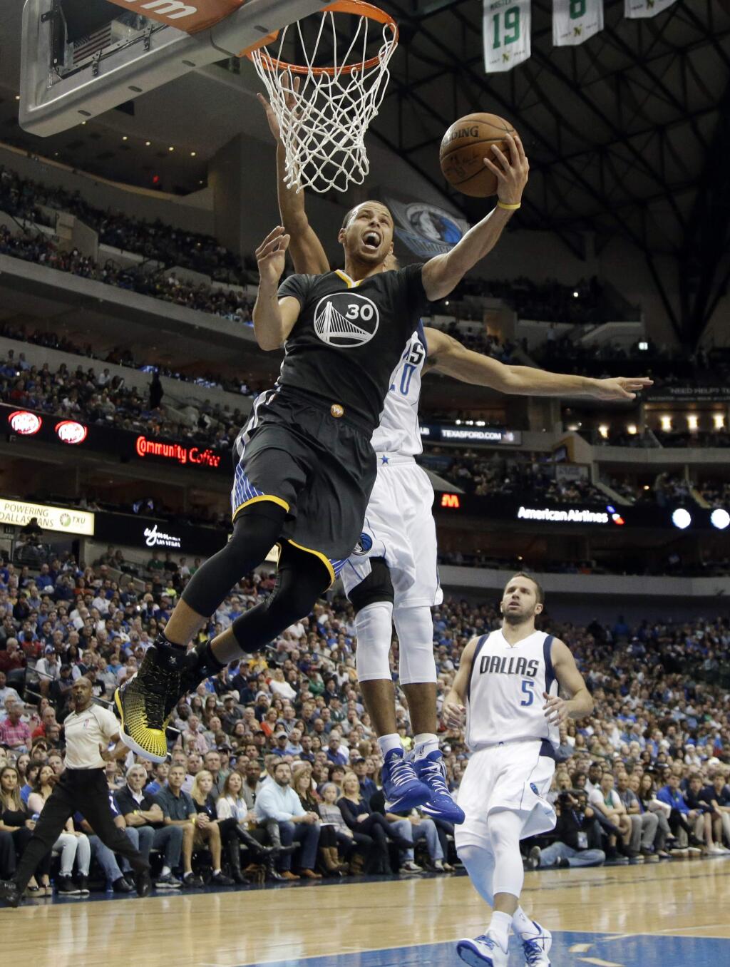 Golden State Warriors guard Stephen Curry (30) gets by Dallas Mavericks' Devin Harris, rear, for a reverse layup in the first half of a game, Saturday, Dec. 13, 2014, in Dallas. (AP Photo/Tony Gutierrez)