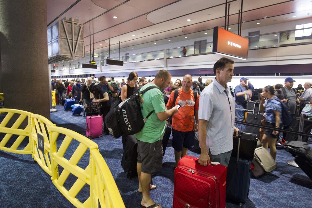 Departing Southwest Airlines passengers wait in line at McCarran International Airport in Las Vegas, Sunday, Oct. 11, 2015. Southwest Airlines is asking travelers on Sunday to arrive at least two hours before their scheduled departures as technical issues are forcing it to check-in some customers manually. (Steve Marcus/Las Vegas Sun via AP)