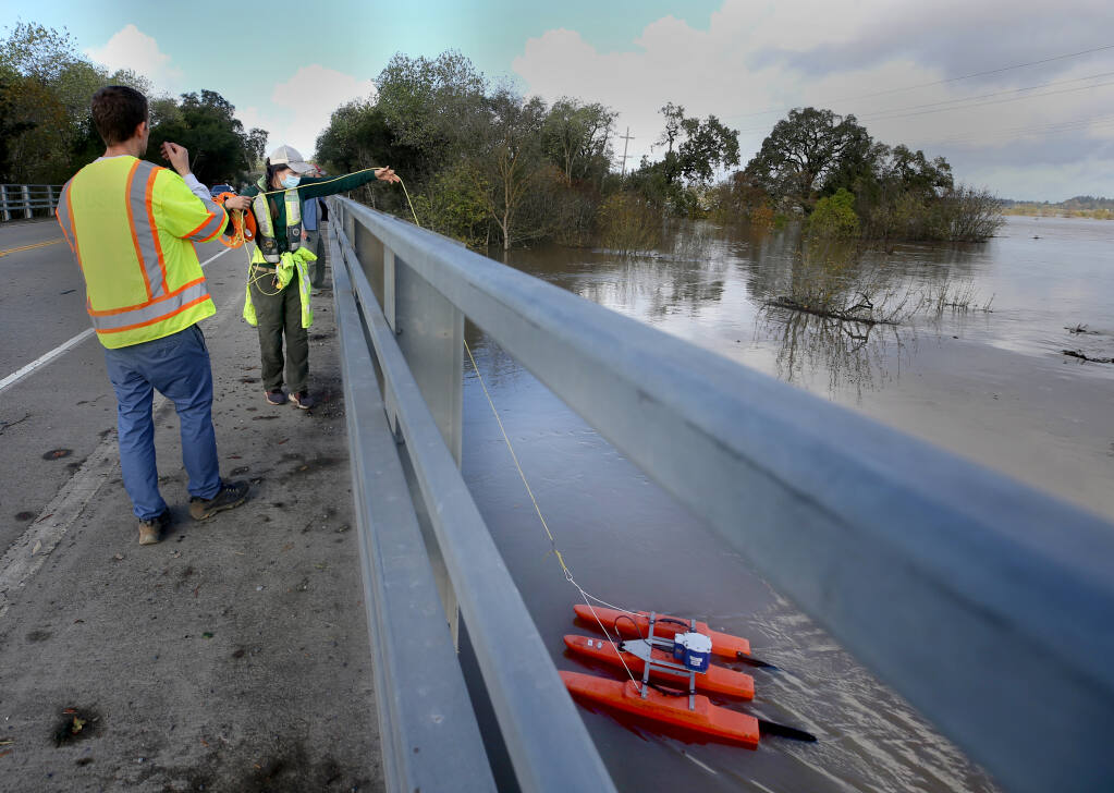 Isabella Karamitsos, a hydrologic technician with the USGS, and Andrew Watson, a field office chief, guide a device that measures water flow in the Laguna de Santa Rosa in Sebastopol, Calif., on Monday, October 25, 2021.(Beth Schlanker/The Press Democrat)