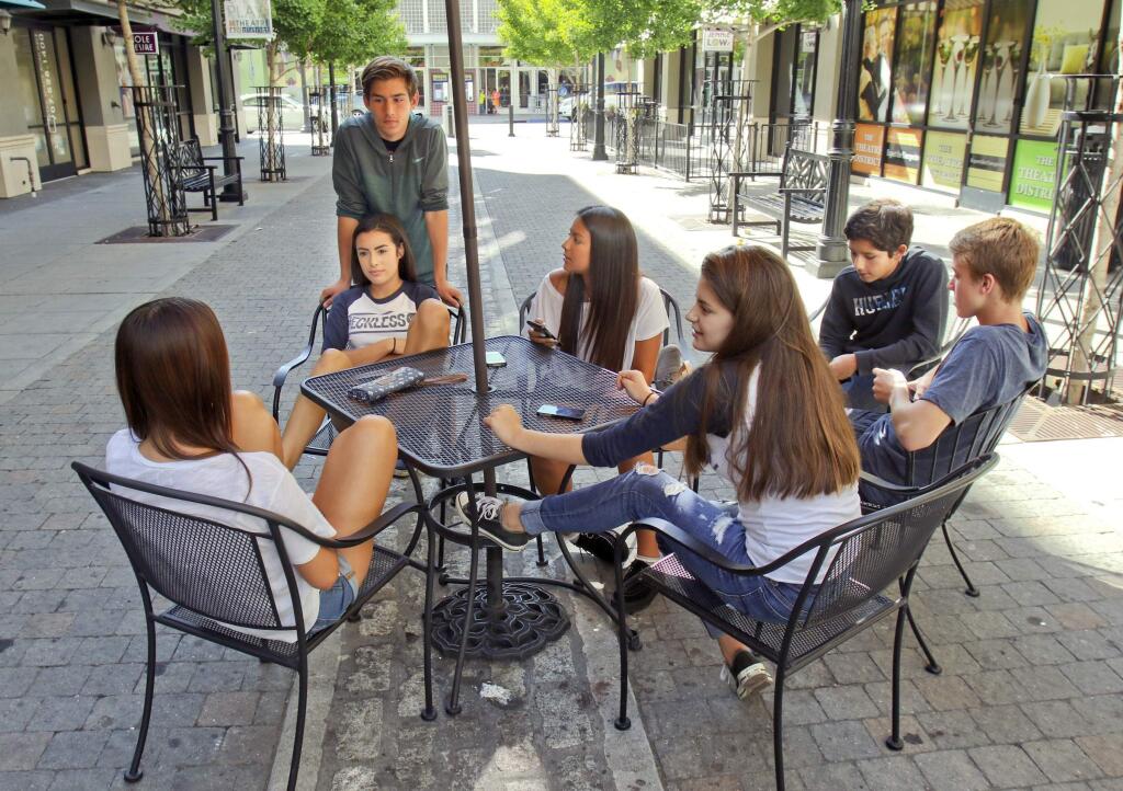 Clockwise from top of photo, Logan Fabiani,14, Mia Shew, 14, Nicole Jimenez, 13, Anthony Avitia, 14, Ian McKissick, 14, Ariana Mitchell, 14, Alex Lemos, 14, hang out in Theater Square in Petaluma on Monday afternoon, July 13, 2015. (SCOTT MANCHESTER/ARGUS-COURIER STAFF)