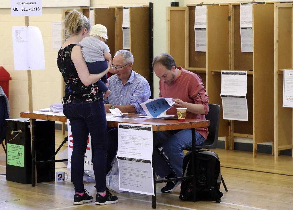 A woman holding a baby casts her vote at a polling station to vote in the referendum on the 8th Amendment of the Irish Constitution, in Dublin, Friday, May 25, 2018. Voters throughout Ireland have begun casting votes in a referendum that may lead to a loosening of the country's strict ban on most abortions. (Niall Carson/PA via AP)