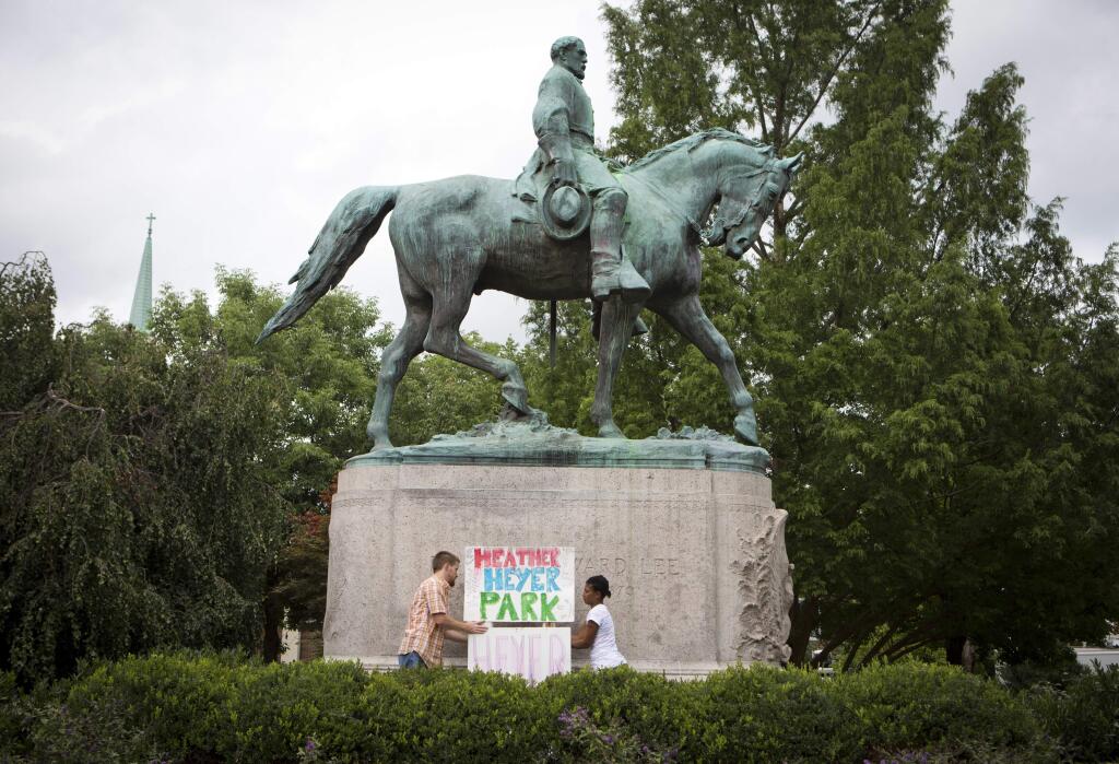 Tom Lever, 28, and Aaliyah Jones, 38, both of Charlottesville, put up a sign that says 'Heather Heyer Park' at the base of the Confederate general Robert E. Lee monument in Emancipation Park Tuesday, Aug. 15 in Charlottesville, Va. Alex Fields Jr., is charged with second-degree murder and other counts after authorities say he rammed his car into a crowd of counterprotesters, including Heyer, Saturday, where a white supremacist rally took place. (AP Photo/Julia Rendleman)