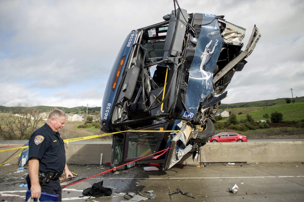 FILE - In this Jan. 19, 2016, file photo, a California Highway Patrol officer moves belongings from a Greyhound bus crash that left two dead and 13 injured in San Jose, Calif. The National Transportation Safety Board said in a report Tuesday, March 28, 2017, that inadequate highway markings caused the fatal bus crash. (AP Photo/Noah Berger, File)