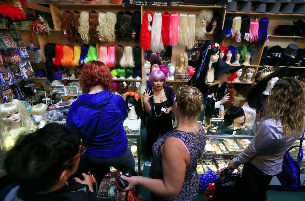 Iliana Sanchez, in pink hair, had her hands full selling makeup and wigs for Halloween at Disguise the Limit in Santa Rosa on Saturday, Oct. 29, 2016. (John Burgess / The Press Democrat, 2016)