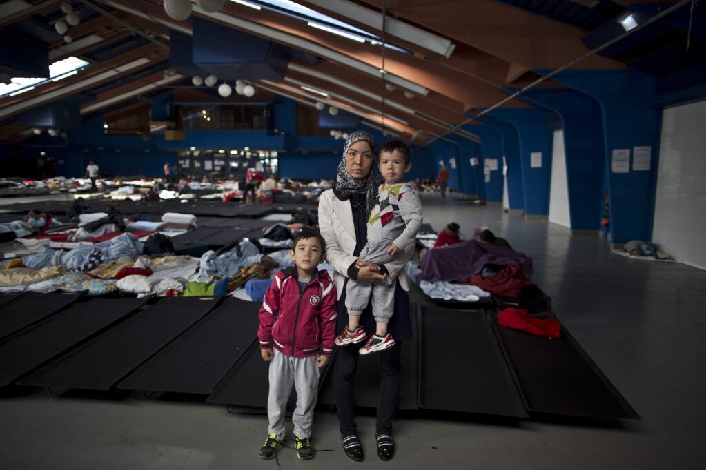In this photo taken on Tuesday, Sept. 22, 2015, Iranian Hamideh Salehi, 38, center and her children Ali, 6, left, and Hussein, 2, who came from Mashhad, Iran, pose for a picture in a shelter where they took refuge near Graz, Austria. 'Weeks of walking was very difficult for my children, the cold in the nights, we were hungry and thirsty, we walked for so long and I had to carry my children. I am happy I am here at this shelter in Austria, I dream of freedom and a good education for my kids that's all I want,' Salehi said. (AP Photo/Muhammed Muheisen)