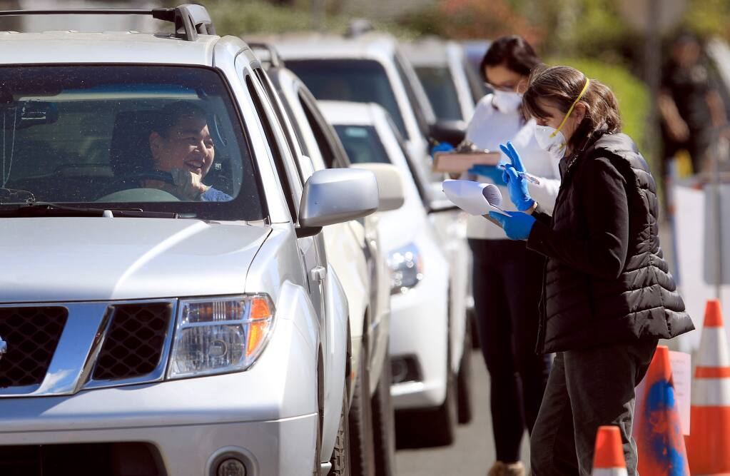 Volunteers with Groceries to Go hand out food to Healdsburg residents during a mobile food giveaway at Healdsburg Elementary School, Thursday, March 26, 2020. (Kent Porter / The Press Democrat) 2020