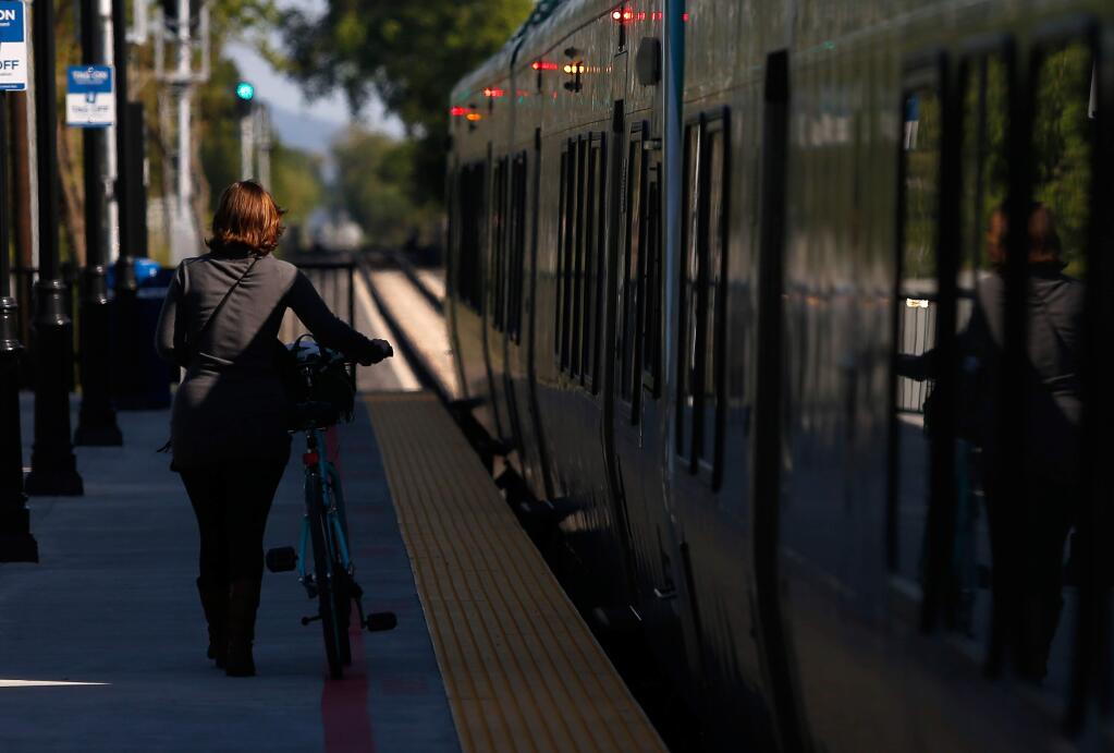 A passenger walks her bicycle down the platform to board the southbound SMART train at the station near Sonoma County Airport, in Santa Rosa, California, on Thursday, April 26, 2018. SMART announced new grant funding which will be used in conjunction with a ballot measure that, if approved, would be used to build the railway's next connector in Windsor. (Alvin Jornada / The Press Democrat)