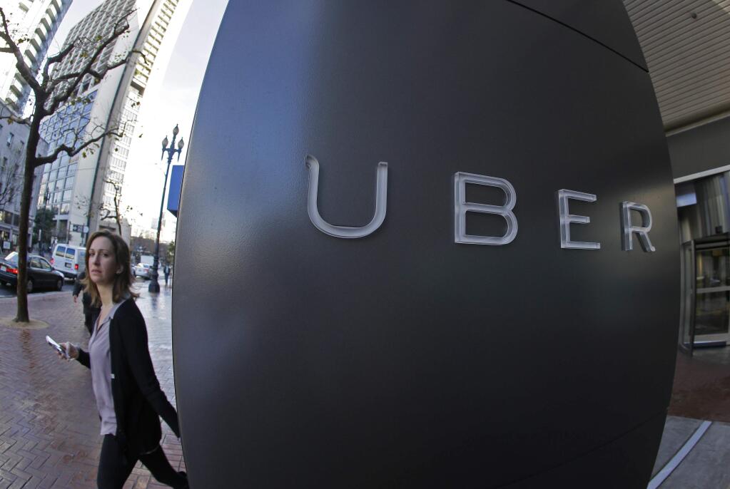 FILE - In this file photo taken Tuesday, Dec. 16, 2014, a woman walks past the company logo of the internet car service, Uber, in San Francisco, USA. Uber's chief executive ordered an urgent investigation Monday Feb. 20, 2017, into a sexual harassment claim made by a female engineer who alleged her prospects at the company evaporated after she complained about advances from her boss. (AP Photo/Eric Risberg, FILE)