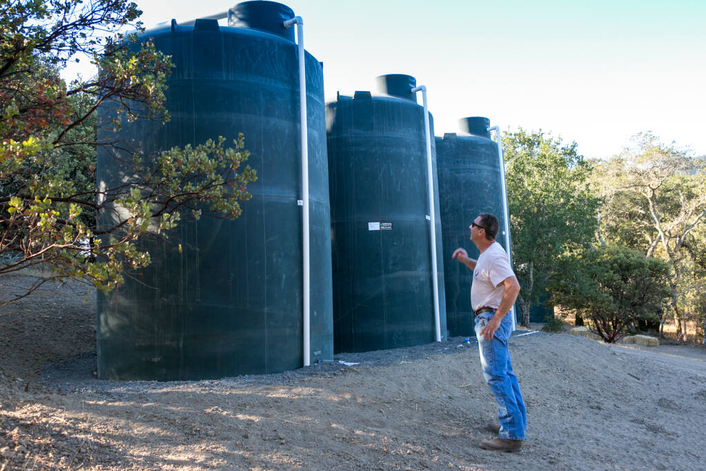 Steve Lee on his Glen Ellen property with three of the 5,000 gallon tanks designed to capture and hold rainwater, Wednesday, Oct. 14, 2020. (Photo by Julie Vader/special to the Index-Tribune)