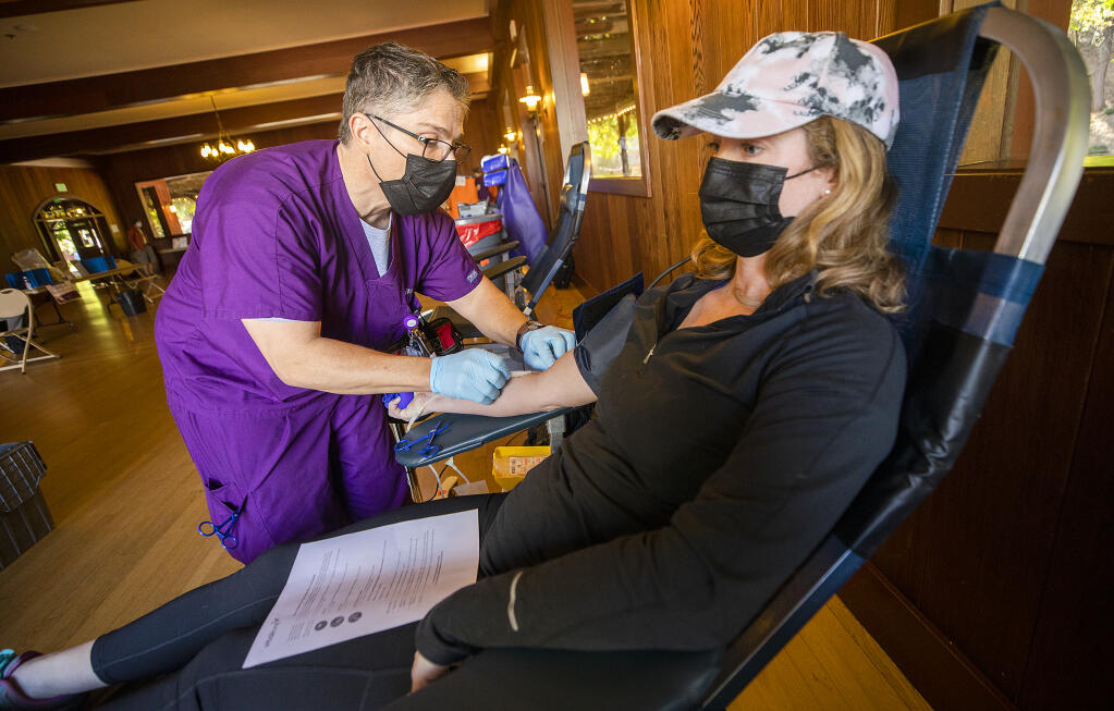Phlebotomist Ian Peña inserts a needle into the arm of Jessica Greene of Geyserville at a Vitalant blood drive at Villa Chanticleer in Healdsburg on Wednesday, Oct. 13, 2021. (John Burgess/The Press Democrat)