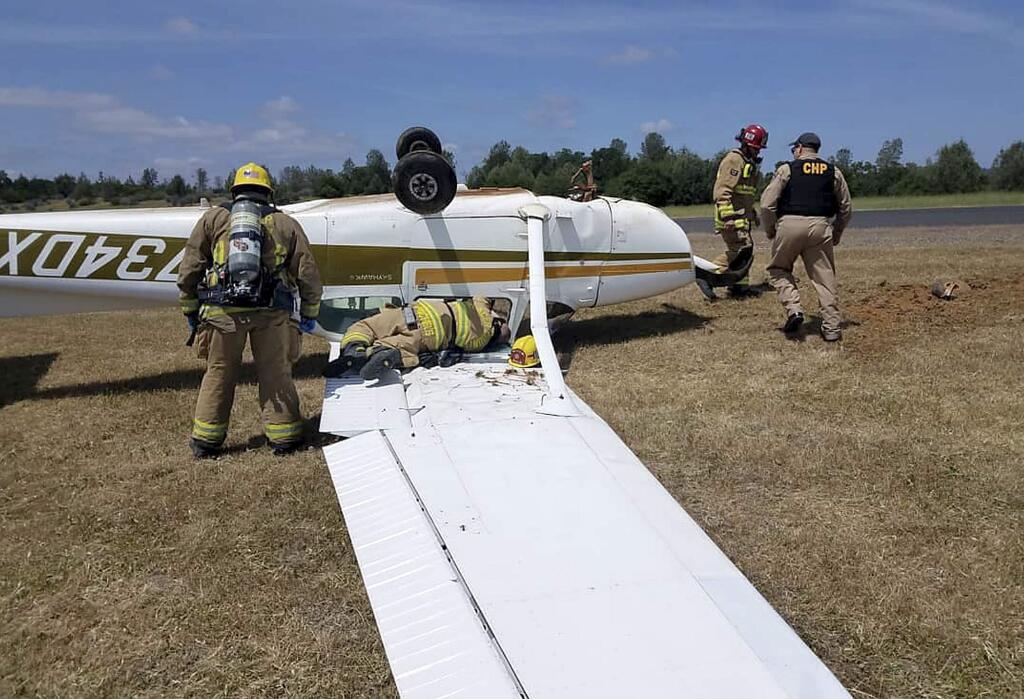 This Monday, May 6, 2019, photo released by CAL FIRE Nevada-Yuba-Placer Unit shows firefighters and officials looking at a plane that crashed in Auburn, Calif. The small plane has flipped over at Auburn Municipal Airport, northeast of Sacramento, but the pilot escaped with only minor injuries. (Mary Eldridge/CAL FIRE Nevada-Yuba-Placer Unit via AP)