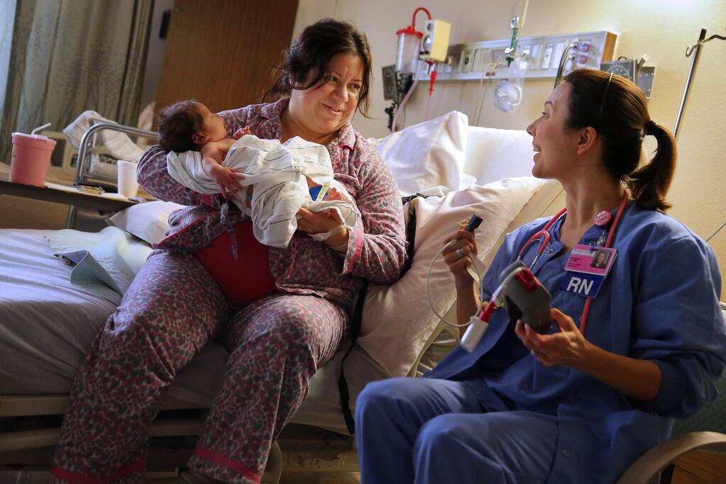 Registered nurse Meghan Gerli, right, talks with Sarah Cox after performing an assessment of her one-day-old son, Ezekiel, in the Family Birthing Center of Petaluma Valley Hospital on Wednesday, January 20, 2016. (Christopher Chung/The Press Democrat)
