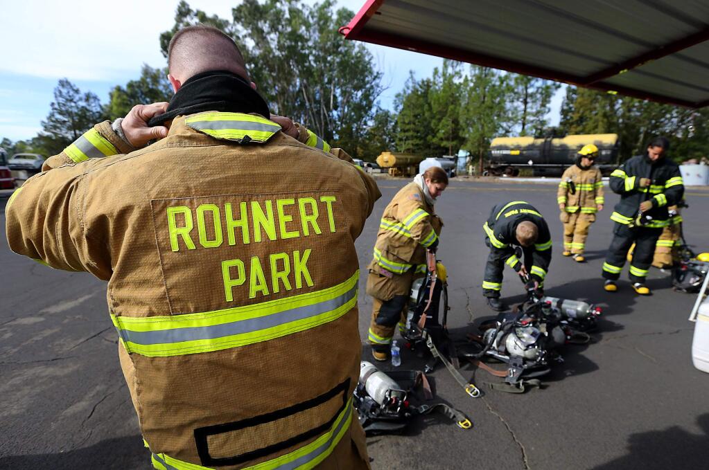 Rohnert Park firefighters put on protective gear and ventilators before entering metal storage containers with a fire inside at the Santa Rosa training tower. (JOHN BURGESS / The Press Democrat)