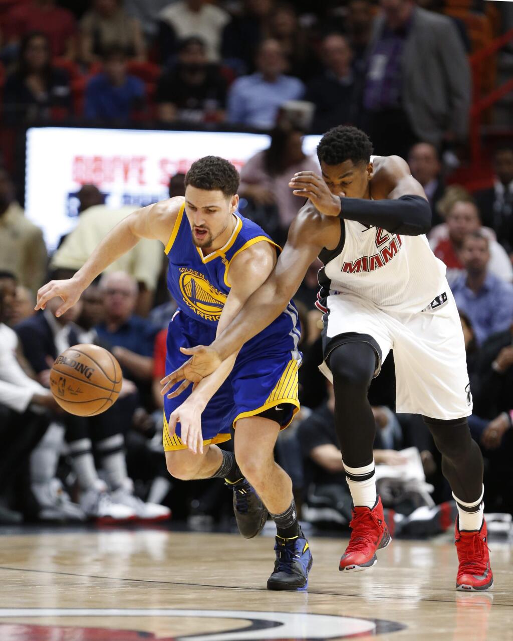 Golden State Warriors guard Klay Thompson, left, and Miami Heat center Hassan Whiteside (21) battle for a loose ball during the first half of an NBA basketball game, Monday, Jan. 23, 2017, in Miami. (AP Photo/Wilfredo Lee)