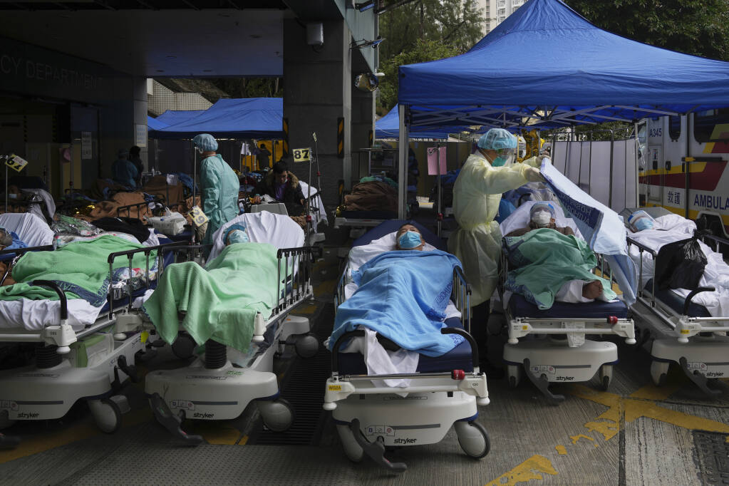 FILE - Patients lie on hospital beds as they wait at a temporary makeshift treatment area outside Caritas Medical Centre in Hong Kong, Friday, Feb. 18, 2022. The World Health Organization downgraded its assessment of the coronavirus pandemic on Friday, May 5, 2023, saying it no longer qualifies as a global emergency. (AP Photo/Kin Cheung, File)