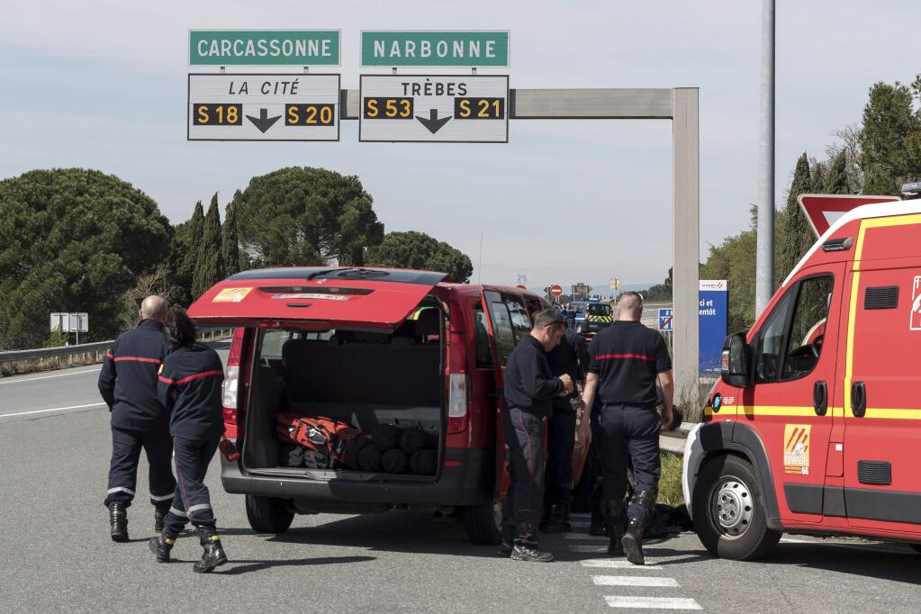 French police and firefighters secure the entrance of Trebes, southern France, where an armed man took hostages in a supermarket, Friday, March 23, 2018. French national police say two people have been killed and about a dozen wounded in a shooting and hostage-taking in a super market in southern France.(AP Photo/Jean-Paul Bonincontro)