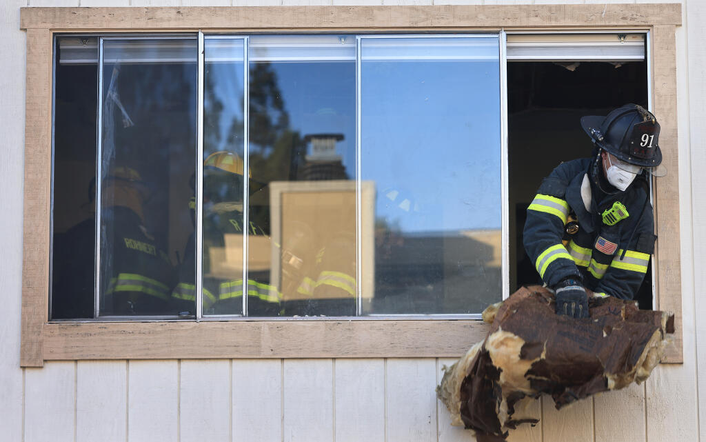 A Rohnert Park Department of Public Safety firefighter discards insulation from an apartment that caught fire at 365 Enterprise Drive in Rohnert Park, displacing several residents, on Thursday, Dec. 21, 2023. (Kent Porter / The Press Democrat) 2023