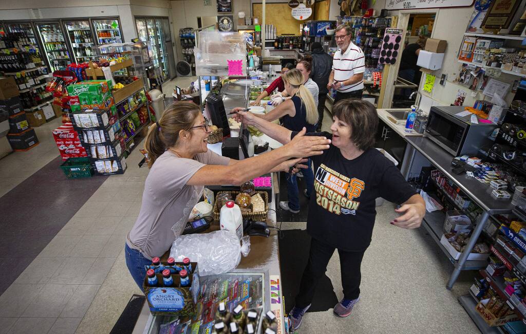 Annie Licardo, left, greets longtime customer Johanna Kolberg at Dave's Market on Third Street and Dutton Avenue in Santa Rosa. The market stayed open in the evacuation zone to serve local customers. (John Burgess/The Press Democrat)