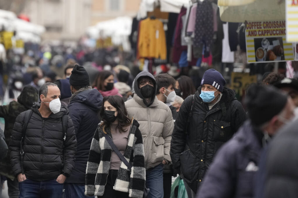 People, some wearing surgical masks, others FFP2 masks, to cope with the surge of COVID-19 cases stroll past stalls at the Porta Portese open air market, in Rome, Sunday, Jan. 9, 2022. Italy, Spain and other European countries are re-instating or stiffening mask mandates as their hospitals struggle with mounting numbers of COVID-19 patients. (AP Photo/Gregorio Borgia)