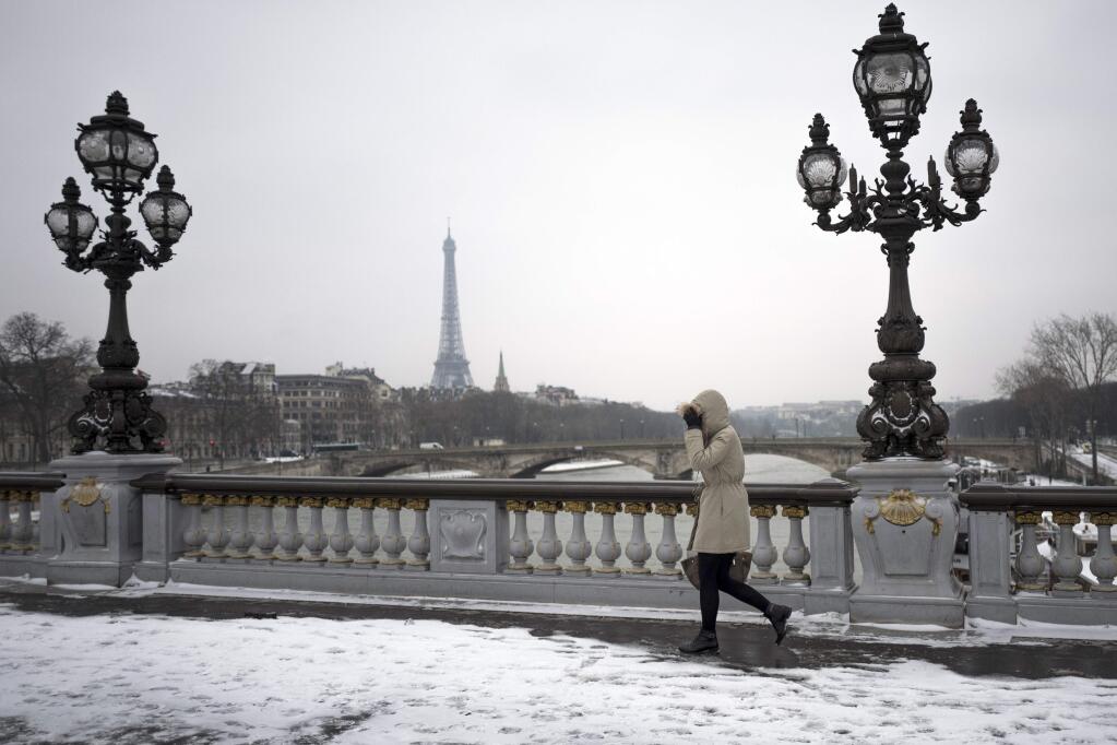 A pedestrian walks on the Alexandre III bridge after overnight snowfalls, in Paris, France, Thursday, March 1, 2018. Snow blanketed Paris and the surrounding region, and authorities urged Paris commuters to leave their cars at home because of dangerous conditions. (AP Photo/Kamil Zihnioglu)