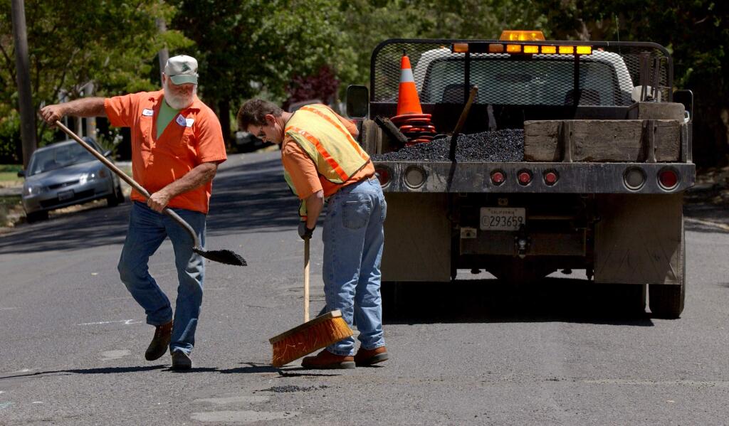 Petaluma maintenance workers fill a pothole along Sixth Street in 2004. (PD FILE)