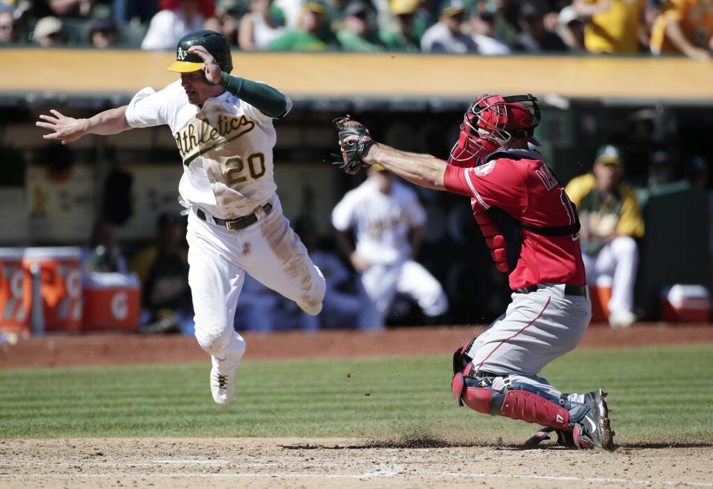 Oakland Athletics' Josh Donaldson, left, is tagged out at the plate by Los Angeles Angels catcher Chris Iannetta as he tried to score on a sacrifice fly from Derek Norris during the fourth inning of a baseball game on Wednesday, Sept. 24, 2014, in Oakland, Calif. (AP Photo/Marcio Jose Sanchez)