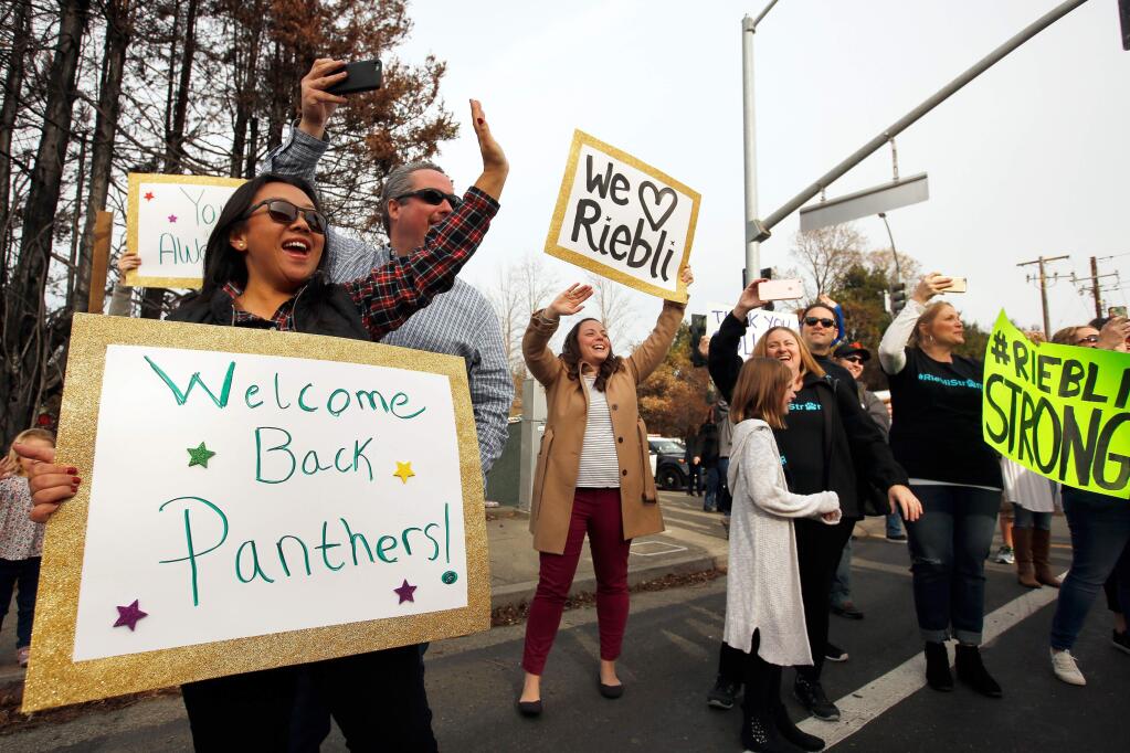 Emery Bodell, left, Annie Buxbaum, center, and other parents enthusiastically wave to busloads of students who are returning to John B. Riebli Elementary School for the first time since the Tubbs Fire damaged the school and decimated the surrounding neighbhorhood in the Larkfield-Wikiup neighborhood of Santa Rosa, California on Friday, December 22, 2017. (Alvin Jornada / The Press Democrat)