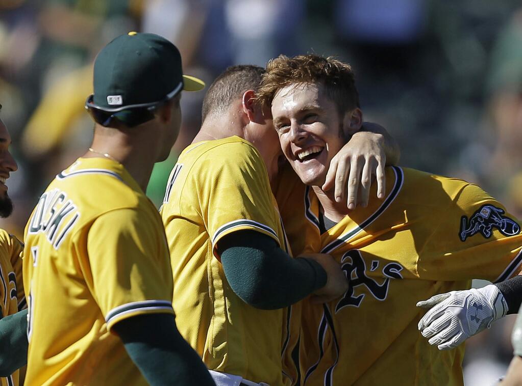 The Oakland Athletics' Mark Canha, right, is embraced after hitting a walk-off home run off the Seattle Mariners' Shae Simmons in the ninth inning Wednesday, Sept. 27, 2017, in Oakland. (AP Photo/Ben Margot)