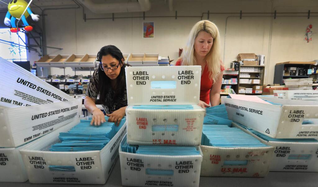 Senior elections specialist Ibon Suazo and elections manager Valerie Walston search through mail in ballots that need to be reviewed by Registrar of Voters managers for signature problems, Friday, June 8, 2018 in Santa Rosa. (Kent Porter / The Press Democrat) 2018