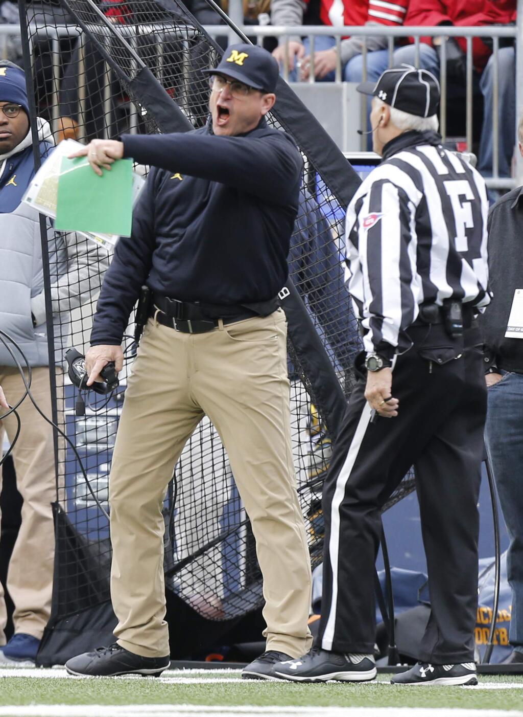 Michigan coach Jim Harbaugh, left, yells at the field judge during the first half of a game against Ohio State, Saturday, Nov. 26 in Columbus, Ohio. Ohio State beat Michigan 30-27 in double overtime. (AP Photo/Jay LaPrete)