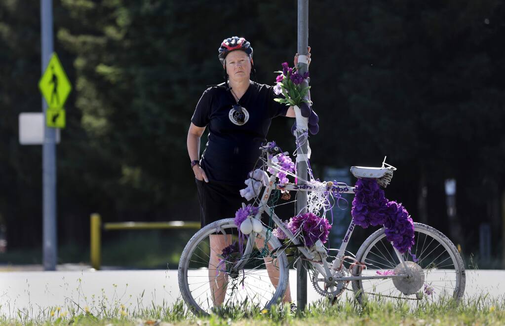 Eris Weaver, the Executive Director of the Sonoma County Bicycle Coalition, stands next to a 'ghost bike' memorial for the late Sidney Falbo on Stony Point Rd at the intersection of Hwy 12 and the Joe Rodota Trail in Santa Rosa on Friday, June 7, 2019. (BETH SCHLANKER/ The Press Democrat)