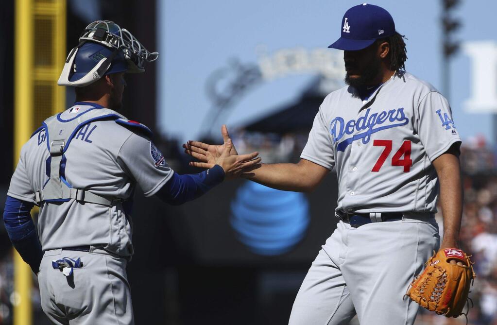 Los Angeles Dodgers' Yasmani Grandal, left, and Kenley Jansen (74) celebrate a win over the San Francisco Giants after a baseball game Sunday, April 8, 2018, in San Francisco. (AP Photo/Ben Margot)