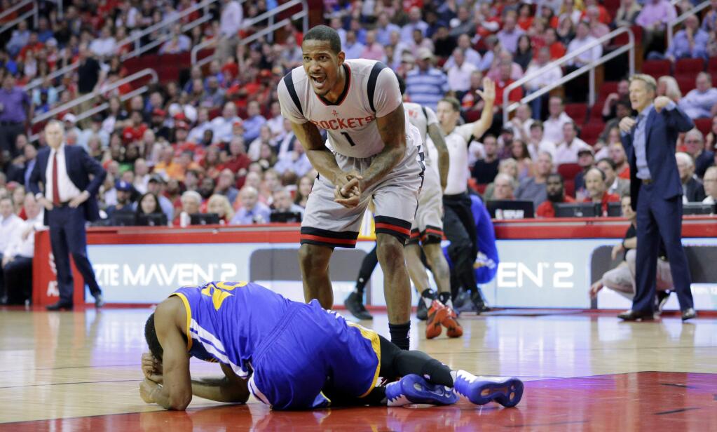 As Golden State Warriors' James Michael McAdoo lies on the court, Houston Rockets' Trevor Ariza tries to get the officials' attention to stop play in the first half of an NBA basketball game in Houston, Sunday, March 28, 2017. Ariza landed on McAdoo's head as they both fell chasing a loose ball. (AP Photo/Michael Wyke)