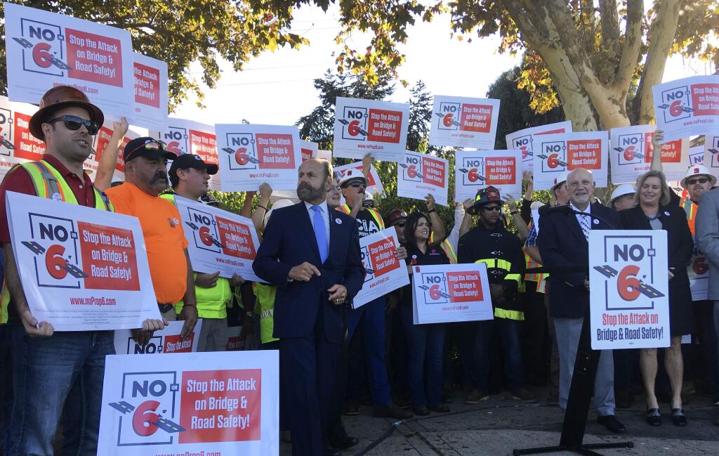 Protestors gather at a rally and hold signs on behalf of a campaign against Proposition 6 during a visit and support by Gov. Jerry Brown on Friday Nov. 2, 2018 in Palo Alto, Calif. Proposition 6, which would repeal an increase in gas tax and vehicle fees for transportation projects in California. (AP Photo/Janie Har)