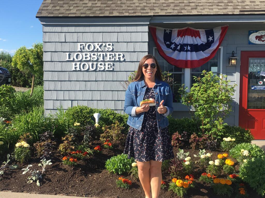 In this Friday, June 7, 2019, photo provided by Alicia Jessop, Jessop poses for a photo with a lobster roll at Fox's Lobster House in York, Maine. Jessop wanted to snap the perfect picture Friday of her lobster roll from Fox's Lobster House in York, Maine, before she took a bite. She says she was focused on framing the sandwich with the picturesque Nubble Lighthouse in the background when she felt something rustle her hand. She quickly realized a seagull had knocked it out of her hand and was already eating it. (Alicia Jessop/@rulingsports via AP)