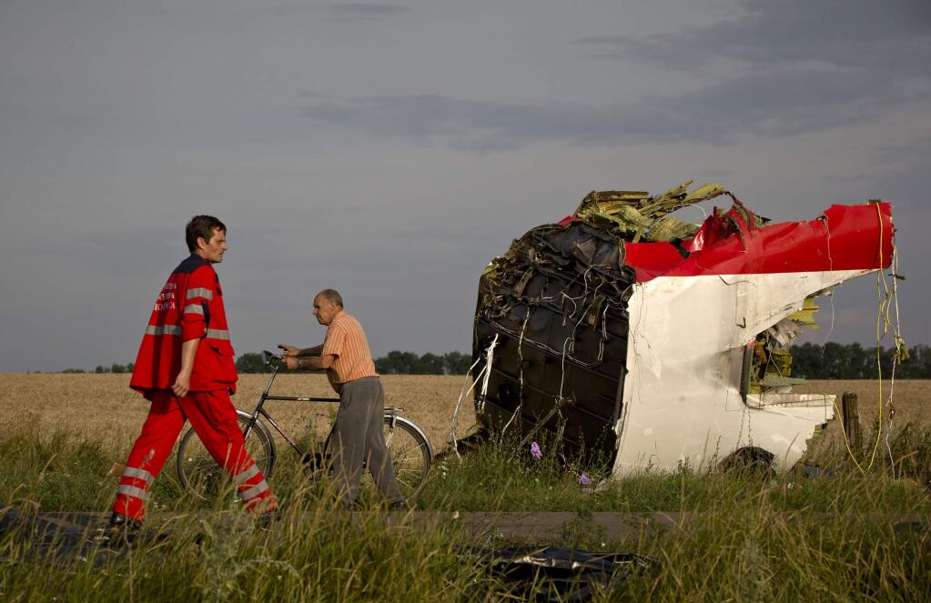 A paramedic walks by a part of fuselage at the crash site of Malaysia Airlines Flight 17 near the village of Hrabove, eastern Ukraine, Saturday, July 19, 2014. World leaders demanded Friday that pro-Russia rebels who control the eastern Ukraine crash site of Malaysia Airlines Flight 17 give immediate, unfettered access to independent investigators to determine who shot down the plane. (AP Photo/Vadim Ghirda)