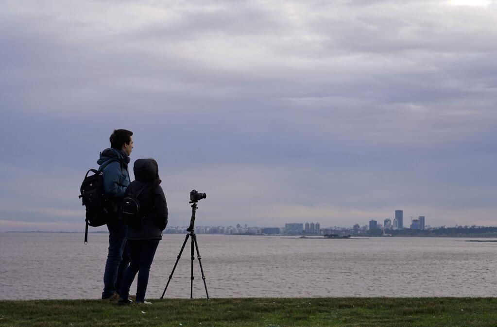 A couple waits to see a solar eclipse, to be seen partially in Montevideo, Uruguay, Tuesday, July 2, 2019. A solar eclipse occurs when the moon passes between the Earth and the sun and scores a bull's-eye by completely blocking out the sunlight. (AP Photo/Matilde Campodonico)