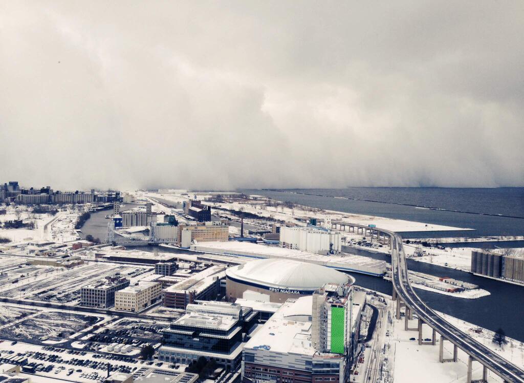 A band of storm clouds moves across Lake Erie and into Buffalo, N.Y., Tuesday, Nov. 18, 2014. Parts of New York measured the season's first big snowfall in feet, rather than inches, on Tuesday as 3 feet of lake-effect snow blanketed the Buffalo area and forced the closure of a 132-mile stretch of the state Thruway. (AP Photo/Gary Wiepert)