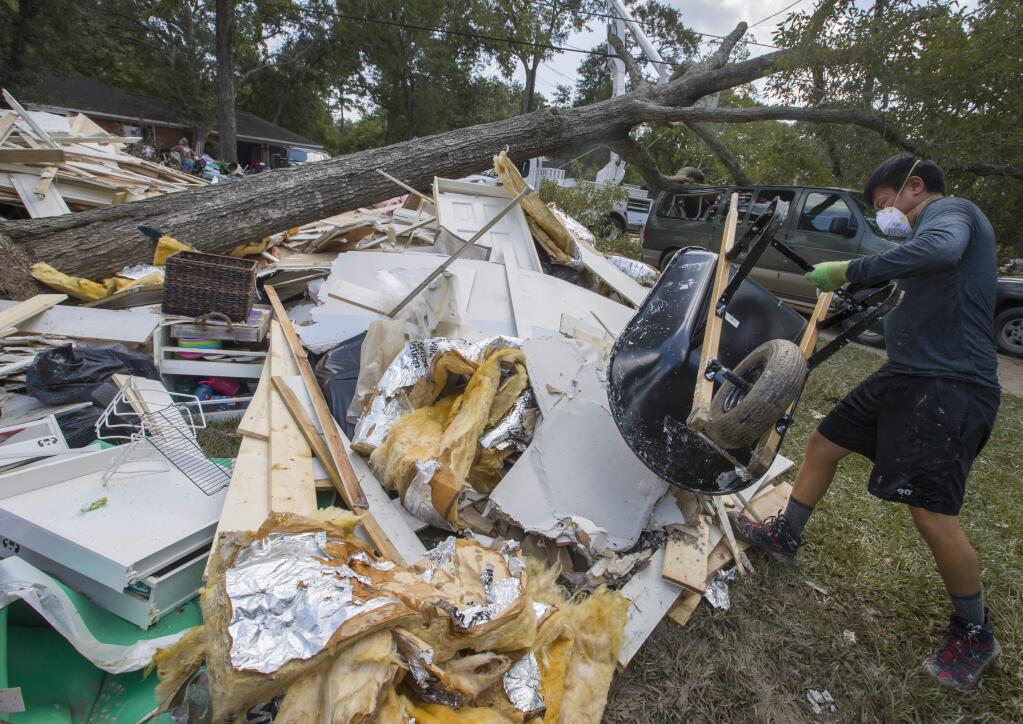 Volunteer Tim Huong empties a wheelbarrow full of debris outside of a flood damaged house in Friendswood, Texas, Thursday, Aug. 31, 2017. (Stuart Villanueva/The Galveston County Daily News via AP)