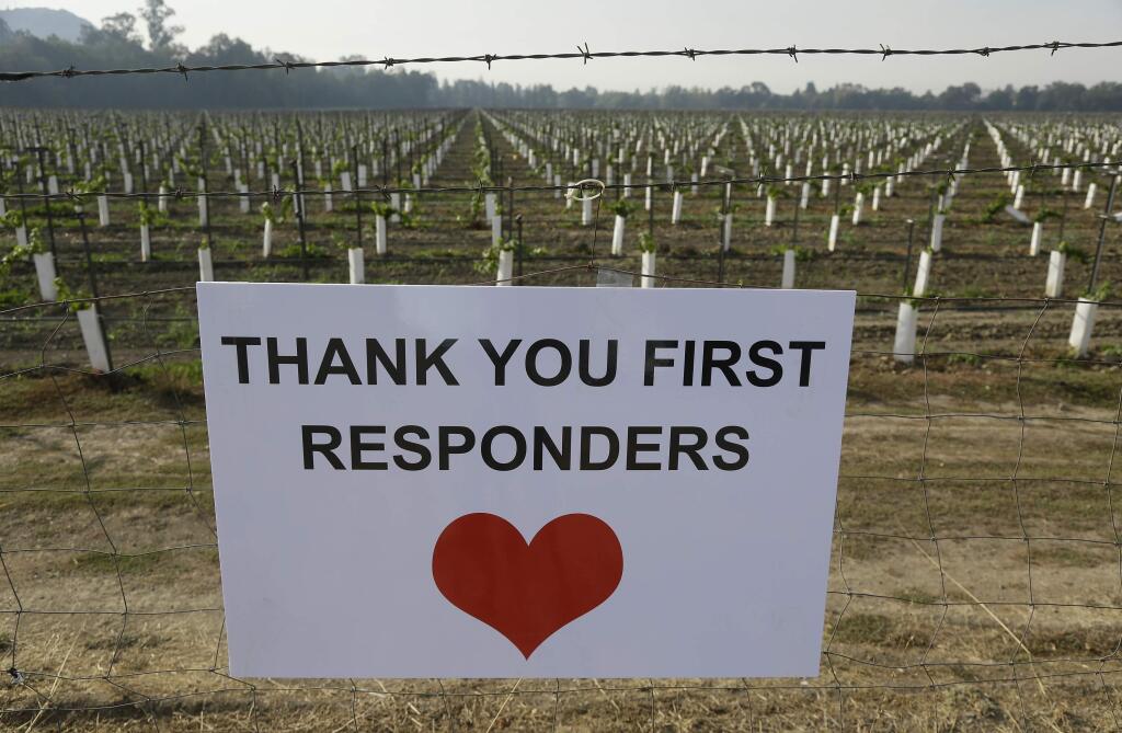A sign thanking first responders hangs by a newly planted vineyard Monday, Oct. 16, 2017, in Napa, Calif. With the winds dying down, fire crews gained ground as they battled wildfires that have devastated California wine country and other parts of the state over the past week, and thousands of people got the all-clear to return home. (AP Photo/Eric Risberg)