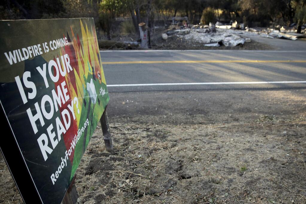 A sign, untouched by fire, stands across the road from a burned-out home that was destroyed by the Kincade Fire near Geyserville, Calif., Thursday, Oct. 31, 2019. The fire started last week near the town of Geyserville in Sonoma County north of San Francisco. (AP Photo/Charlie Riedel)